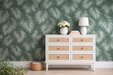 Papel pintado con plantas minimalistas sobre un tono turquesa, instalado en una pared. 