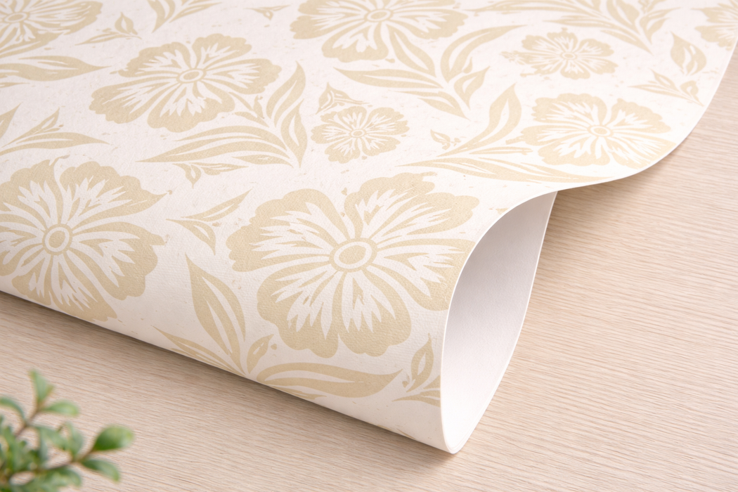 Detalle de esquina de papel pintado con estampado de flores en tonos beige y fondo blanco roto.
