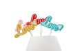 Picks decorativos Love en varios colores colocados sobre base blanca