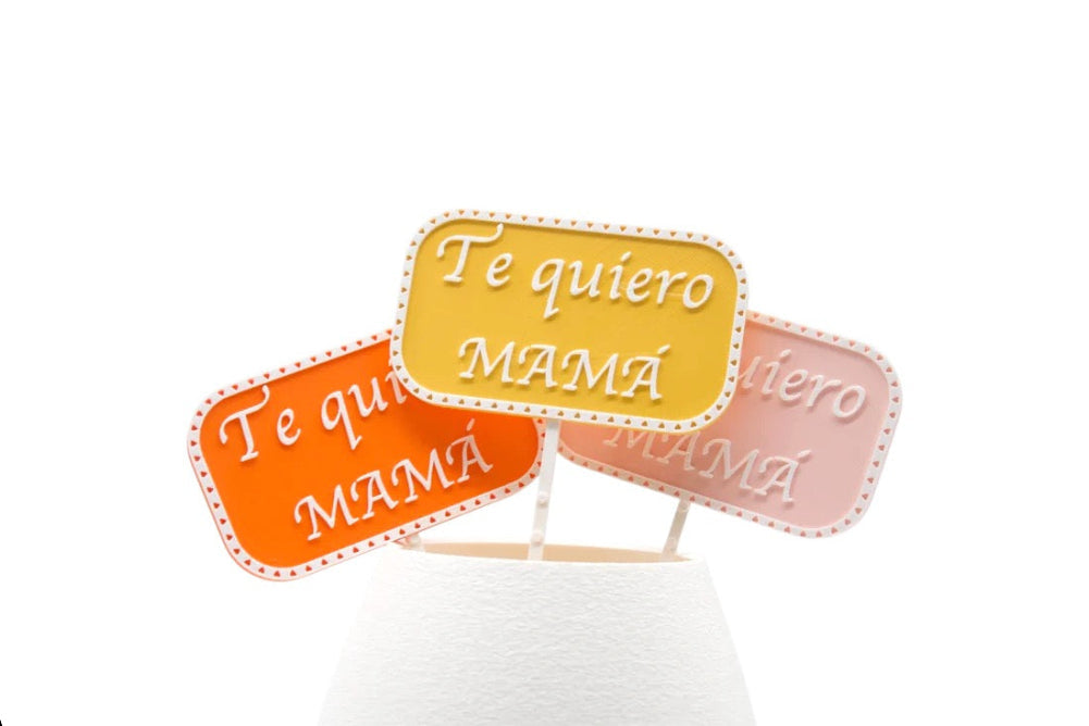 Picks decorativos Te Quiero Mamá en distintos colores colocados sobre base blanca