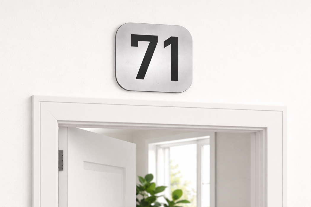Placa número 71 bicapada plateada instalada en puerta de entrada para señalización de vivienda