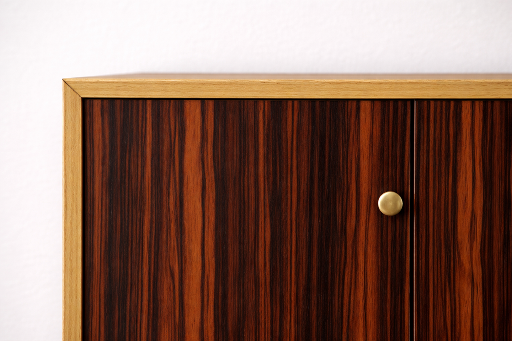 Detalle del vinilo efecto madera oscura cálida colocado en la esquina de un mueble